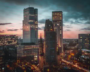 Decorative cityscape photograph of Berlin Germany skyline at sunset with illuminated modern office buildings and historic architecture