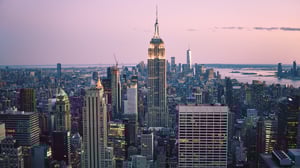 Decorative cityscape photograph of New York skyline at dusk featuring Empire State Building and Manhattan office towers with pink sunset sky