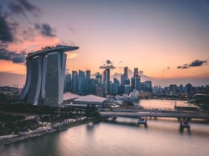 Singapore skyline at sunset with Marina Bay Sands hotel, keylight on iconic tower, modern skyscrapers, river, and bridge at dusk